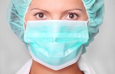 Diplomirana medicinska sestra z masko in kapo — delo v zdravstveni negi